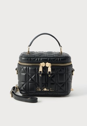 Sac à main en cuir noir matelassé avec des fermetures éclair dorées, une poignée supérieure et une bandoulière amovible sur fond blanc.