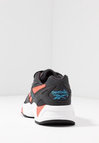 Czarno-szare buty sportowe z pomarańczowymi akcentami. Posiadają miękki kołnierz, paneli z siateczki oraz białą podeszwę środkową. Logo Reebok w kolorze niebieskim.