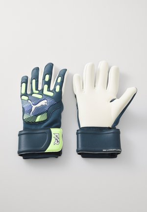 Guanti da portiere con un design blu navy e bianco, materiali in lattice, accenti di presa e un cinturino verde con branding sul polso.