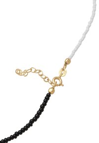 Collier de perles alternant des perles noires et blanches, équipé de ferrures dorées et d'un fermoir en forme de homard avec une chaîne réglable pour personnaliser la longueur.