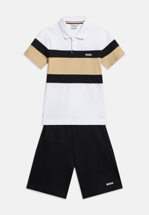 Witte poloshirt met zwarte en beige horizontale strepen en zwarte korte broek, beide met kleine witte "BOSS"-logo's.