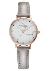 Montre ronde avec un cadran à motif marbre blanc, accents en or rose et un bracelet en cuir gris. Possède des index en cristal et des aiguilles simples.