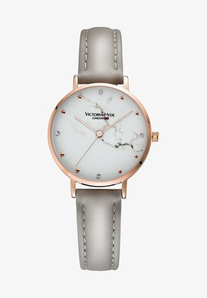 Rund ur med en hvid marmor-mønsteret urskive, roseguld accenter og en grå læderrem. Har krystal timemarkører og enkle visere.