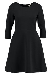 Svart klänning med åtsittande överdel och utsvängd kjol. Tillverkad av ett texturerat tyg med ribbat mönster och trekvartsärmar. Dragkedja bak.