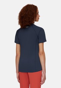 Kurzärmliges, marineblaues Sportshirt mit figurbetontem Schnitt, ausgestattet mit einem hohen Kragen und Flachnaht für zusätzlichen Komfort. Minimale Markenkennzeichnung am Halsausschnitt.