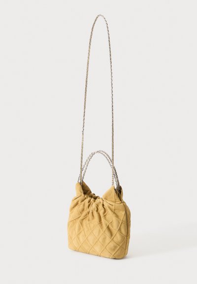 Sac à main matelassé jaune moutarde doux avec des bretelles en chaîne argentée courtes et longues, présenté sur un fond blanc uni.