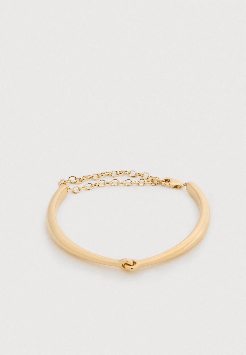 Bracelet de couleur or avec un design lisse et courbé et une extension à maillons de chaîne. Dispose d'un fermoir simple pour une fixation sécuris ée.