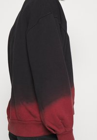 Sweatshirt tinto a mano in nero e rosso, con colletto rotondo, maniche lunghe e tessuto testurizzato con una finitura liscia.