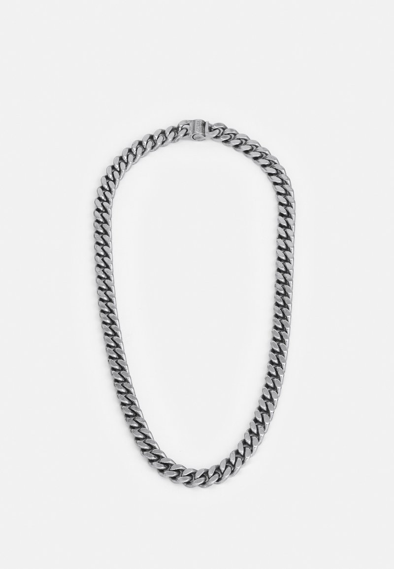 Collier chaîne épaisse couleur argent avec un fermoir, posé à plat sur fond blanc.