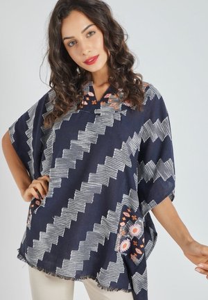 Top estilo kimono de color azul marino con patrones en zigzag, detalles blancos y bordados florales. Cuenta con escote en V y un dobladillo con flecos.