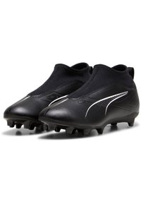 Scarpe da calcio nere con superficie texturizzata, design a caviglia aderente e strisce bianche sui lati. Presentano tacchetti modellati per una maggiore trazione.