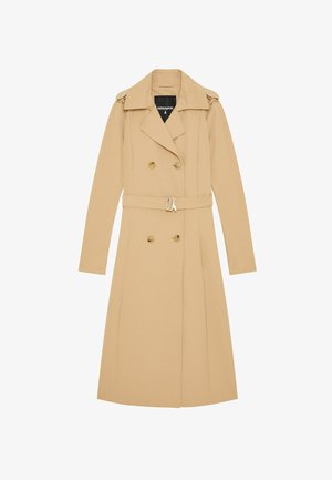 Cappotto beige a lunghezza ginocchio realizzato in tessuto morbido, caratterizzato da una chiusura doppiopetto, spalline e una cintura con fibbia metallica.