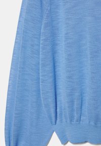 Hellblauer Strickstoff mit gerippten Bündchen und Saum, der die Textur und den Fall des Stoffes zeigt.