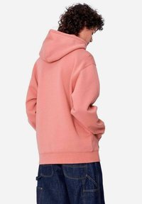 Sudadera con capucha de suave tela rosa, con un corte holgado y puños acanalados. La parte trasera presenta un acabado liso sin logotipos visibles.