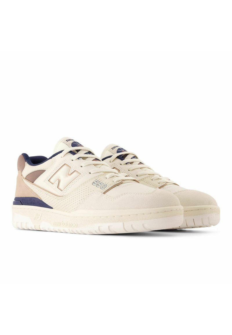 Cremige Wildleder-Sneaker mit marineblauen und beigen Akzenten, ausgestattet mit einem perforierten Design, gepolstertem Kragen und einer weißen Gummisohle. Modell 550.