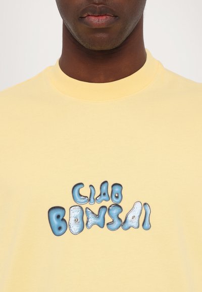 Geel katoenen t-shirt met een ronde hals, met een glanzende blauwe en witte 'Ciao Bonsai' print op de voorkant.