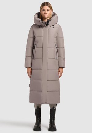 Lange, lichtgrijze puffercoat met een capuchon, rits-zijzakken en een stikselontwerp. Gladde textuur, knielang, gecombineerd met zwarte laarzen.