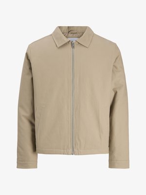 Bež jakna na patentni zatvarač s vrhovnim ovratnikom, dugim rukavima i dva prednja džepa, prikazana na bijeloj pozadini.