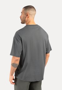 Grå kortærmet t-shirt med afslappet pasform, simpel design og glat tekstur, set fra ryggen. Ingen synlige mønstre eller accenter.