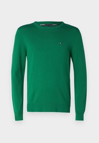 Pull vert à manches longues avec col rond, poignets et ourlet côtelés, arborant un petit logo Tommy Hilfiger rouge, blanc et bleu sur la poitrine.