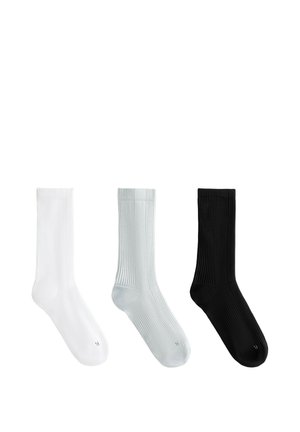 Trois chaussettes côtelées blanches, gris clair et noires, chacune marquée d’un "R" au niveau des orteils.