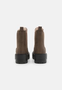 Botine maronii cu căptușeală din blană moale, talpă neagră rezistentă și un design simplu. Prezintă două mânere pentru o încălțare ușoară.