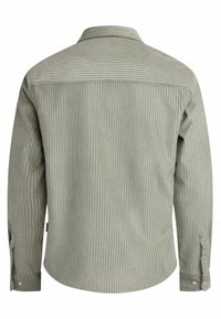 Camisa de pana a rayas verdes con mangas largas, un cuello puntiagudo y puños con botones. Presenta un dobladillo recto y una tela texturizada.