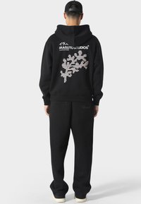 Zwarte hoodie met grafisch ontwerp op de achterkant. Tekst en patroon in wit en roze. Gekocht met bijpassende zwarte trainingsbroek.