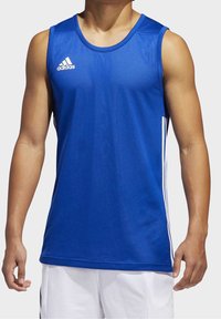 En man som bär en ärmlös blå Adidas sporttröja med vita ränder på sidorna och vita shorts mot en enhetlig bakgrund.