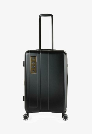 Maleta rígida negra con rayas verticales, mango retráctil y cuatro ruedas. Presenta un logo de DKNY chapado en oro en la parte frontal.