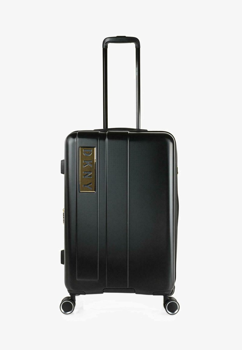 Maleta rígida negra con rayas verticales, mango retráctil y cuatro ruedas. Presenta un logo de DKNY chapado en oro en la parte frontal.