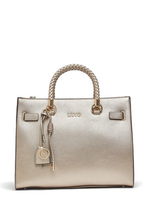 Arany textúrájú kézitáska fonott fogantyúkkal, díszes rojttal és logó medállal, valamint a LIU JO márkanévvel a középső elején.