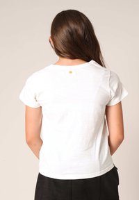 Witte katoenen t-shirt met korte mouwen, relaxte pasvorm, zichtbare stiksels en een klein gouden accentdetail op de achterkant van de halslijn.