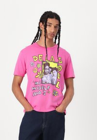 Pink cotton t-shirt with graphic print featuring flowers, peace signs, and black-and-white photo. Crew neck, short sleeves, relaxed fit.