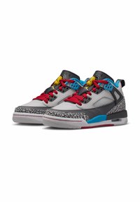 Un paio di scarpe da ginnastica grigie e nere con lacci rossi, accenti blu e fermagli gialli, caratterizzate da un motivo testurizzato distintivo sui lati.