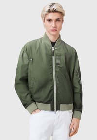 Olive green bomber jacket with zip front, ribbed collar, and cuffs. Includes side pockets and a zip pocket on the sleeve. Smooth texture.