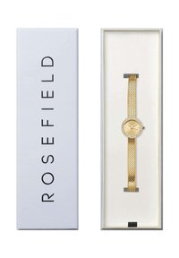 Reloj con correa de malla dorada en una caja blanca. Esfera redonda dorada con acentos de cristal, manecillas de hora y minuto en plata, diseño minimalista.