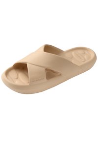 Beige cross-strap slide sandal made of soft rubber-like material. Features a textured footbed and rounded sole with branding on the side.
