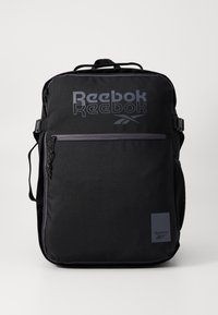 Melnā Reebok mugursoma ar logo, ar rāvējslēdzēja kabatām, regulējamām siksnām, teksturētu audumu un sānu sietiņu ūdens pudelei.