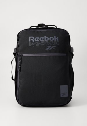 Čierny batoh Reebok s logom, so zipsovými vreckami, nastaviteľnými popruhmi, textúrovanou tkaninou a bočnou sieťovanou kapsou na fľašu s vodou.