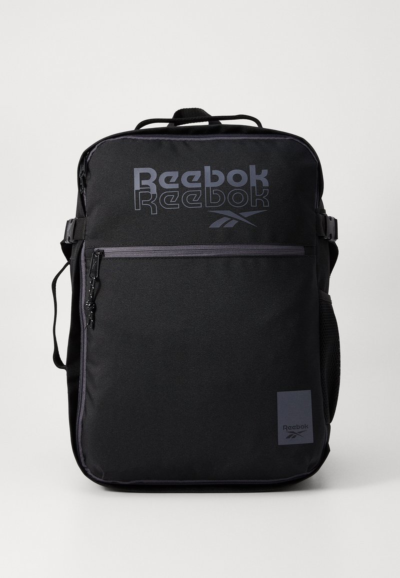 Melnā Reebok mugursoma ar logo, ar rāvējslēdzēja kabatām, regulējamām siksnām, teksturētu audumu un sānu sietiņu ūdens pudelei.