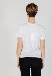 Witte katoenen t-shirt met een ronde hals en korte mouwen, met een zachte textuur en een eenvoudige ontwerp. Gekozen met zwarte broek.