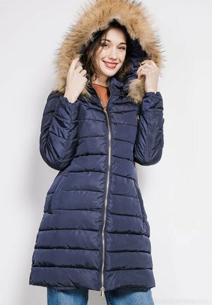 Manteau en duvet marine avec une capuche en fausse fourrure, fermeture éclair à l'avant et texture matelassée. Comprend des poches latérales et une silhouette ajustée.