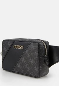 Schwarze Umhängetasche aus Kunstleder mit diagonalem Muster, auffälligem goldfarbenem "GUESS"-Logo, Reißverschluss und verstellbarem Riemen.