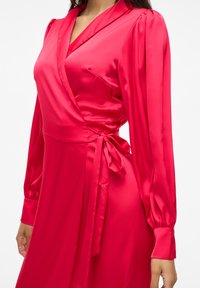 Abito avvolgente in satin rosso con maniche lunghe a sbuffo, scollatura a V profonda e un nastro in vita. Texture liscia e design elegante in tutto l'abito.