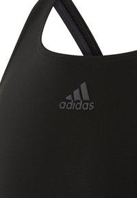 Schwarzer Sport-BH mit glattem, elastischem Stoff und Ringer-Design. Ein dezentes Adidas-Logo in dunklerer Farbe ist auf der Vorderseite angebracht.