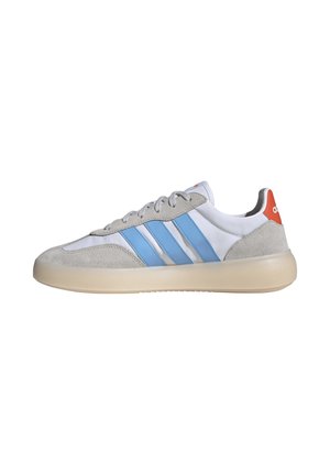 Sneakers med en grå ruskind og hvid syntetisk overdel, der har lyseblå striber og en rød hælkant, med en beige gummisål.
