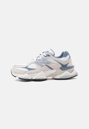 Biało-niebieski sneaker New Balance z teksturą z siateczki i zamszu, z grubą podeszwą i sznurowanym zapięciem, widoczny z lewej strony.