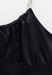 Tissu en satin noir avec encolure froncée et fine bretelle en perles argentées rectangulaires.