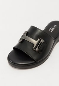 Sandale glissière en cuir noir avec large bride présentant une grande boucle métallique en forme de H et une semelle rembourrée étiquetée Gabor Comfort.